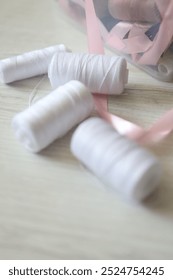 spools of thread. white sewing threads with a pink ribbon on a light background.