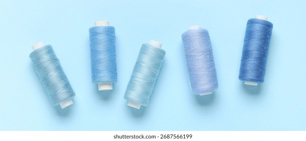 Spools of threads on light blue background, top view