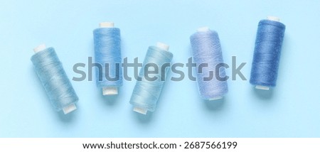 Spools of threads on light blue background, top view