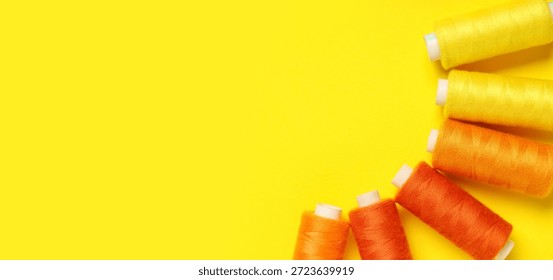Spools of threads on yellow background with space for text, top view