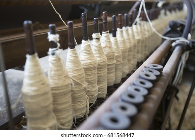 Spools Of White Wool Yarn On Wooden Bobbins In Vintage Factory.