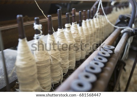 Spools of white wool yarn on wooden bobbins in vintage factory.