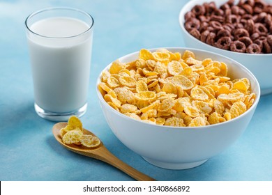 Spoon And Bowl With Chocolate Rings, Yellow Frosted Corn Flakes And A Glass Of Milk For Dry, Cereals Breakfast 