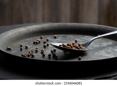 A Spoon And Cilantro Placed On A Black Iron Plate. Image Of Spices. Close-up.