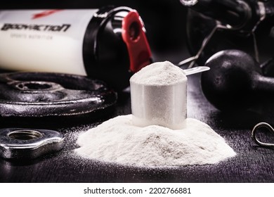 spoon with Creatine, whey or casein, whey supplements, protein bar for physical exercises, gym in the background, muscle mass gain - Shutterstock ID 2202766881