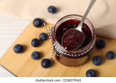 Spoon with delicious blueberry jam and fresh berries on wooden table, above view. Space for text - Shutterstock ID 2258579543
