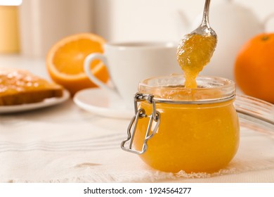 Spoon With Delicious Orange Marmalade Over Jar On Table. Space For Text