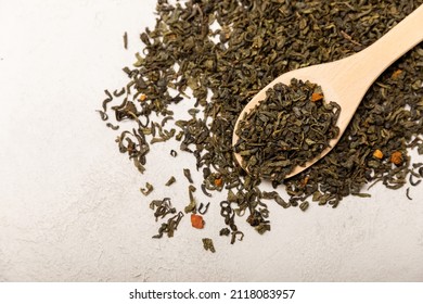 Spoon of dried fragrant green tea leaves on a light cement background. Composition with organic, natural green tea. Copy space.
