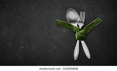 Spoon And Fork Tied With Green Velvet Ribbon On Black Background