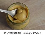 spoon in a glass jar of dijon mustard