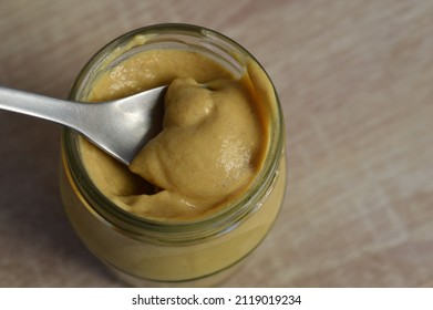 Spoon In A Glass Jar Of Dijon Mustard