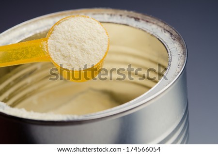 spoon with infant formula on background