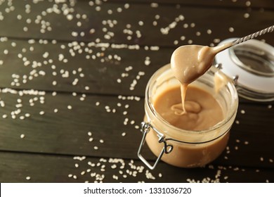 Spoon And Jar With Tasty Tahini On Wooden Table