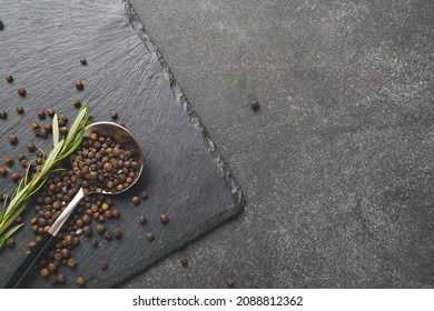 Spoon with peppercorns on dark background