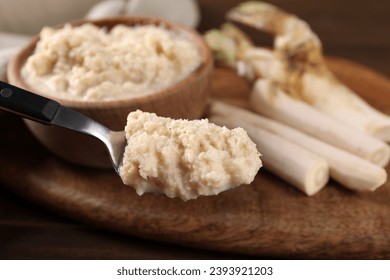 Spoon with spicy horseradish sauce over table, closeup