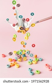 Spoon With Splashing Milk And Falling Cereal Rings On Color Background