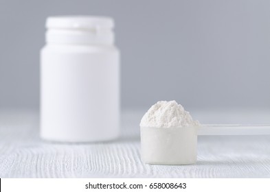 A Spoon With White Powder And A Bottle On Gray Background