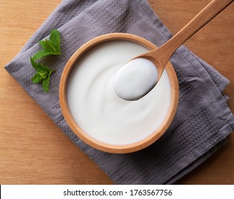 Spoon The Yogurt In A Wooden Bowl. Top View.