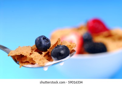 Spoonful Of Crispy Bran Flakes With Fruit With Bowl Of Cereal In The Background