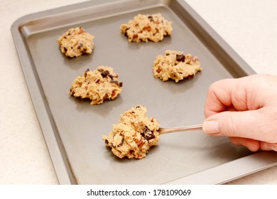 Spooning Chocolate Chip And Pecan Cookie Dough Onto A Baking Sheet