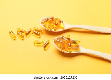 Spoons With Fish Oil Capsules On Color Background