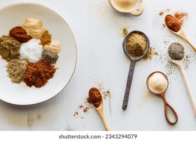 Spoons with messy piles of spices and a piles on a plate with copy space. - Powered by Shutterstock