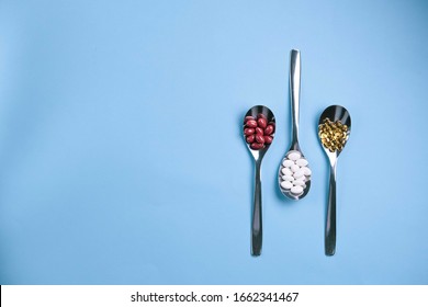 Spoons with pills on a light blue background. Healthy food supplements concept.