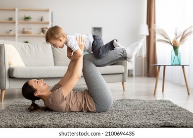 Sport activities with baby. Young mother exercising with her toddler son at home, excited mom balancing kid on knees while training on floor carpet in living room interior, free space - Powered by Shutterstock