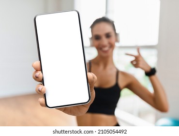 Sport App. Big Blank Smartphone In Hand Of Young Athletic Lady, Cheerful Fit Female Showing Phone With White Screen While Training In Fitness Studio, Recommending New Mobile App, Collage, Mockup