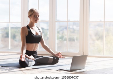 Sport Application, Website. Cheerful Young Woman Practicing Yoga At Home, Using Laptop, Copy Space