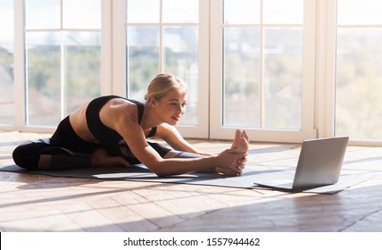 Sport Application, Website. Flexible Young Woman Practicing Yoga At Home, Using Laptop, Copy Space