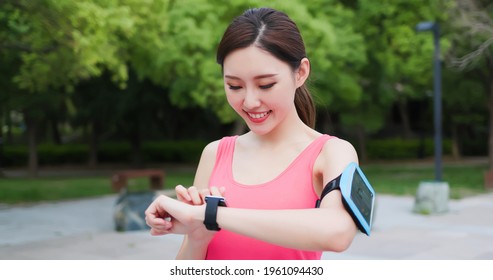 sport asia woman use wearable fitness tracker smart watch and running with smartphone in the park