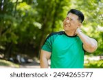 Sport Asian jogger man have shoulder pain, injury concept. Fitness muscular Japanese male has neck pain and shoulders after running having an ache in his arm. Athlete runner pain in joints outdoors.