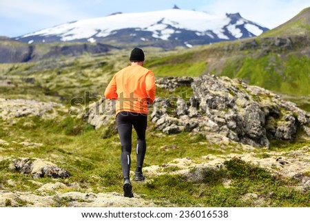 Sport athlete - exercising trail runner running. Active male fitness model training and jogging outdoors in beautiful mountain nature landscape by Snaefellsjokull, Snaefellsnes, Iceland.