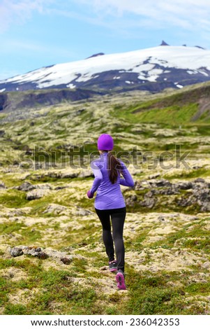 Sport athlete woman - exercising trail runner running. Active female fitness model training and jogging outdoors in beautiful mountain nature landscape by Snaefellsjokull, Snaefellsnes, Iceland.