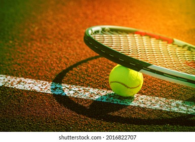 Sport background design dark tone. Closeup tennis ball and racket on line point on clay court.