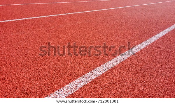 Sport Background. Running track in outdoor. Red\
Jogging rubberized athletic track with a white dividing lines at\
the stadium under the open\
sky.