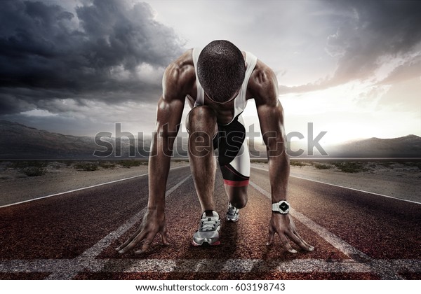 Sport backgrounds. Sprinter on the start\
line of the track befor the dramatic\
sky.