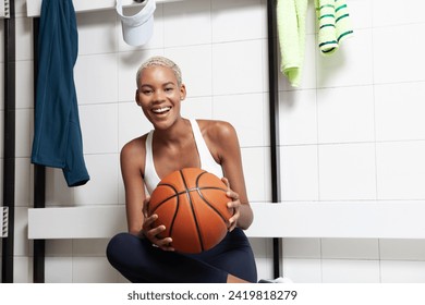 Sport basketball player in the locker room, a smiling African American female athlete holding the ball before the game, competition or training. Woman sitting in changing room with basket ball - Powered by Shutterstock