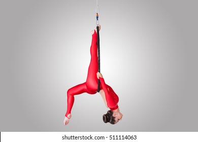 Sport. Beautiful acrobat dancer on aerial silk in studio isolated on grey background. Air acrobatic young women takes the twine isolated