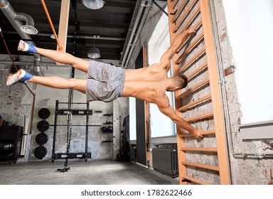 sport, bodybuilding, fitness and people concept - young man exercising on gymnastics wall bars in gym - Powered by Shutterstock