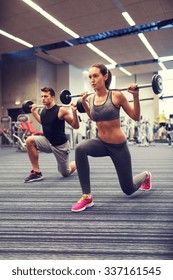 Sport, Bodybuilding, Lifestyle And People Concept - Young Man And Woman With Barbell Flexing Muscles And Making Shoulder Press Lunge In Gym