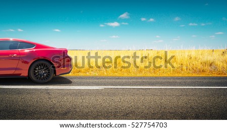 Sport car parked on road side with field of golden wheat background .