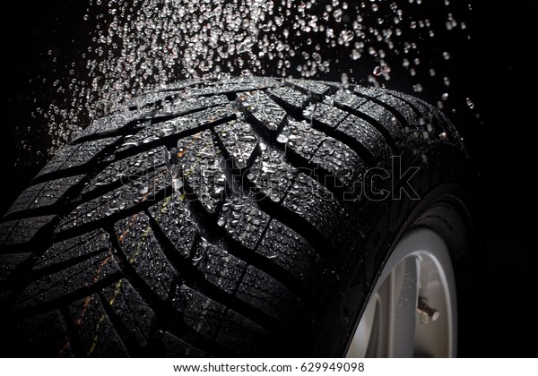 sport car tire\
with water drops against\
black