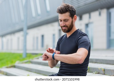Sport Caucasian man looking smart watch at modern track runner using use smartwatch fitness bracelet Portrait fit male athlete checking result jogging in sportswear in street urban city park outdoor