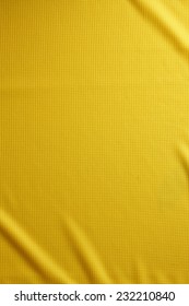 Sport Clothing Fabric Texture Background. Top View Of Cloth Textile Surface. Yellow Football Shirt. Text Space