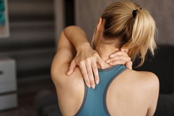 Sport Concept. Athletic Girl Feeling Pain In Her Neck Against Blurred Background. Pain After Home Workout