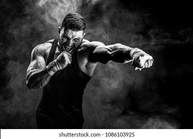 Sport concept. Sportsman muay thai boxer fighting on black background with smoke.