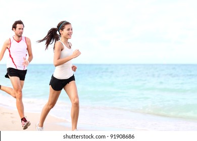 Sport - Couple Running On Beach Training For Marathon Run. Young Multiracial Couple Runners, Smiling Asian Female Fitness Model And Caucasian Male Model.