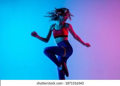 Sport dancing  Beautiful woman in bright sportwear isolated gradient pink  blue background in neon light  Athletic   graceful  Modern sport  action  motion  youth concept  Female practicing
